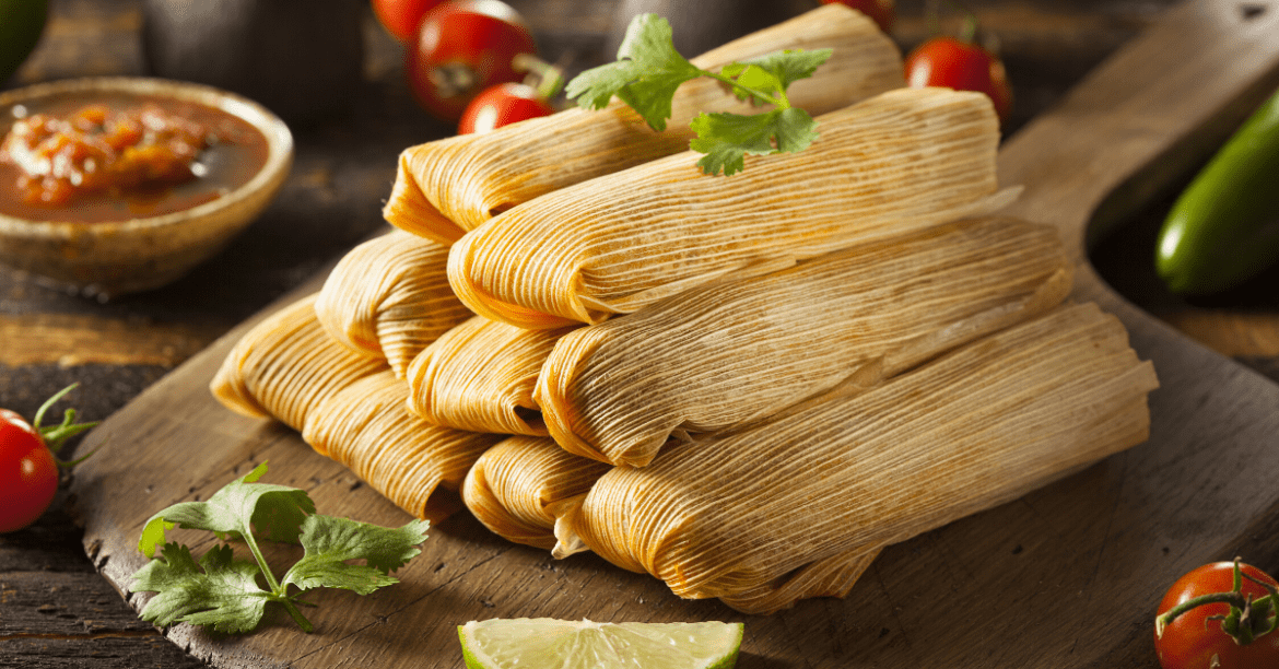 traditional Mexican tamales on a clay plate with sauce bowls on the side